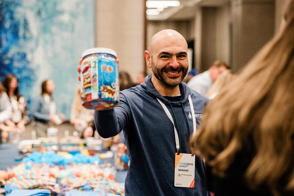 A Geron leadership member smiling while holding a bin at a charity event