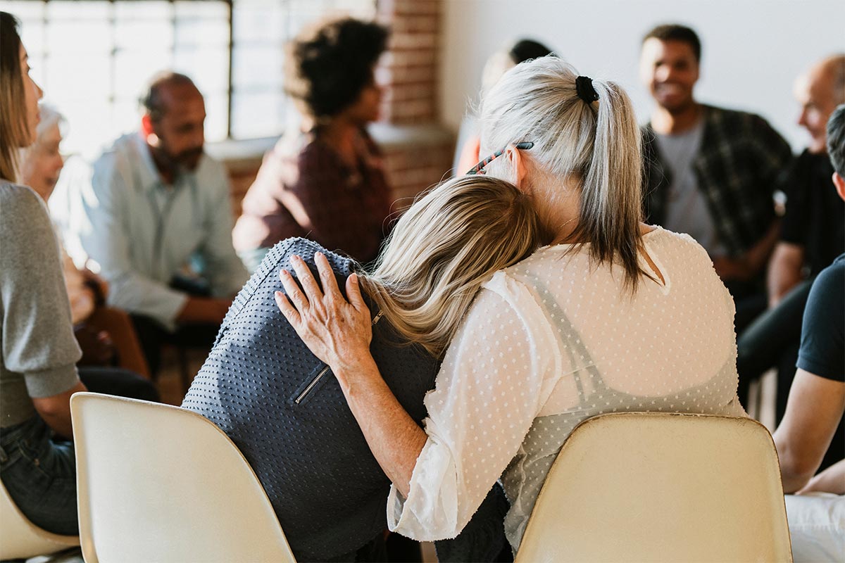 Older woman comforting girl in support group