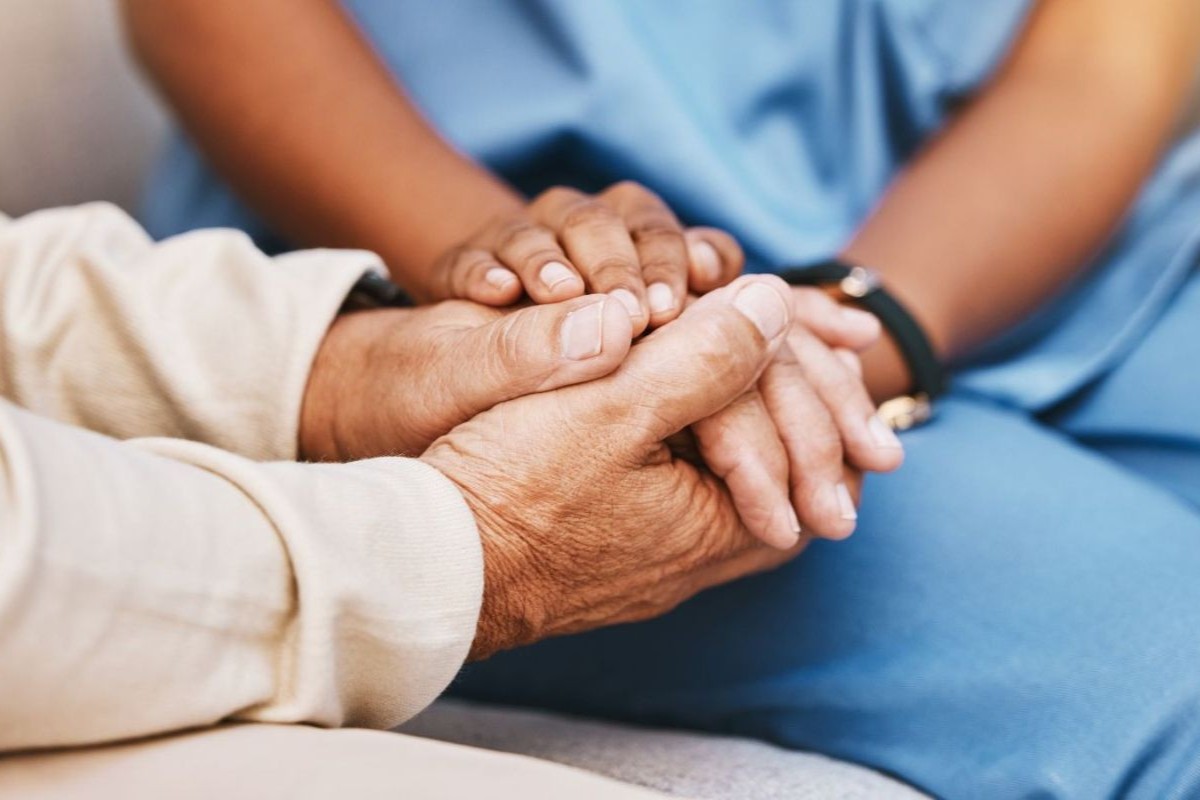 close up of patient and healthcare worker holding hands