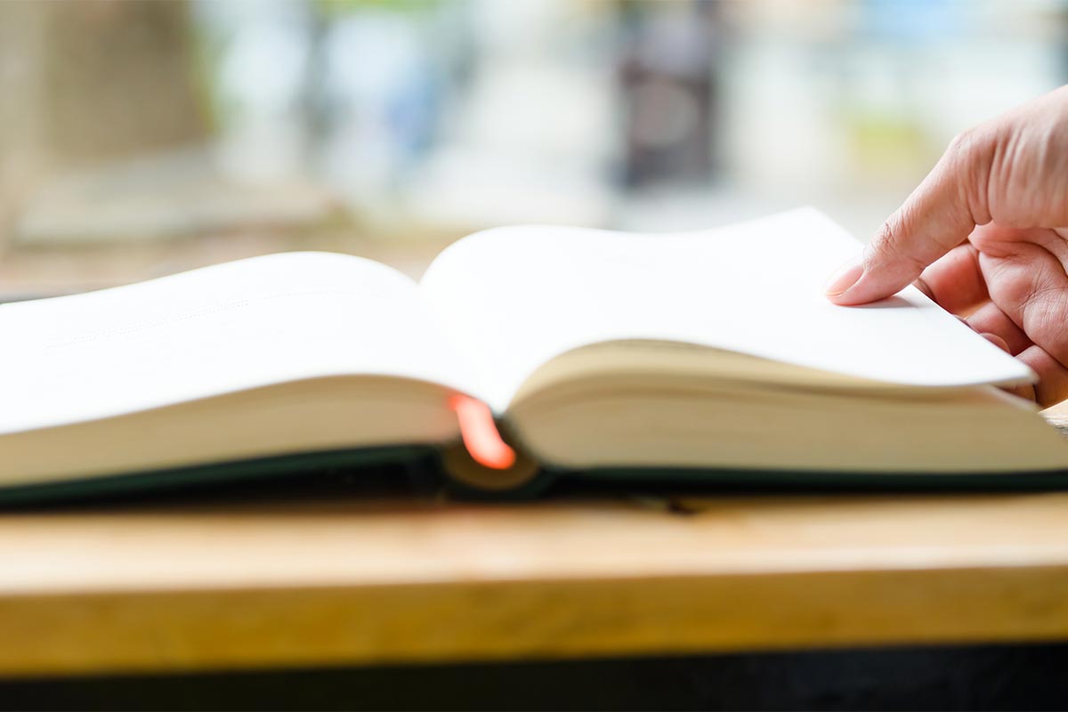upclose image of a persons hand flipping pages in a book temp