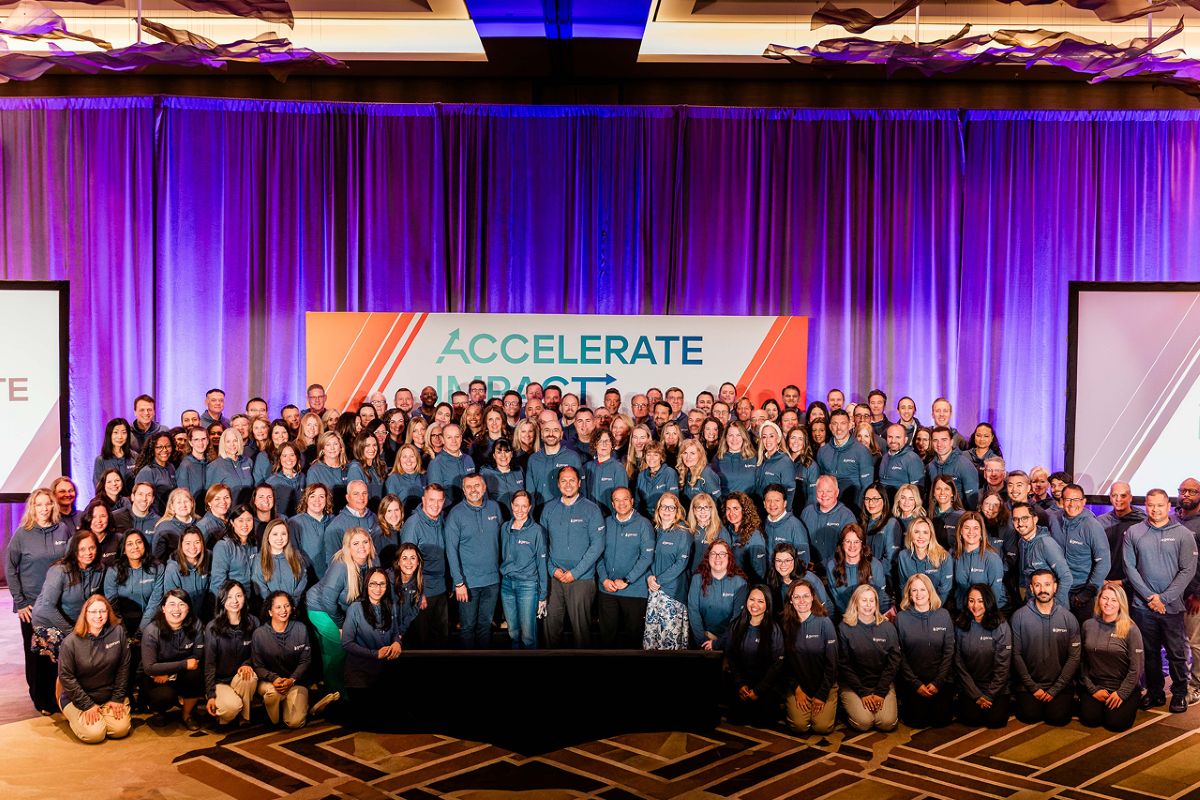 entire geron employee group smiling on stage in ballroom