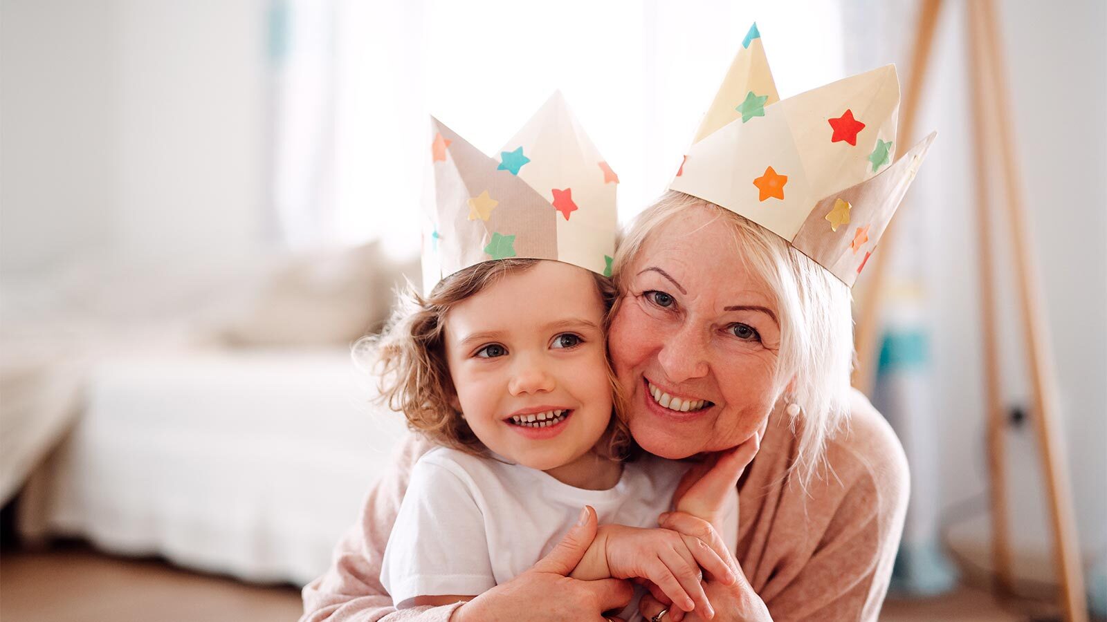A portrait of small girl with grandmother hugging at home.