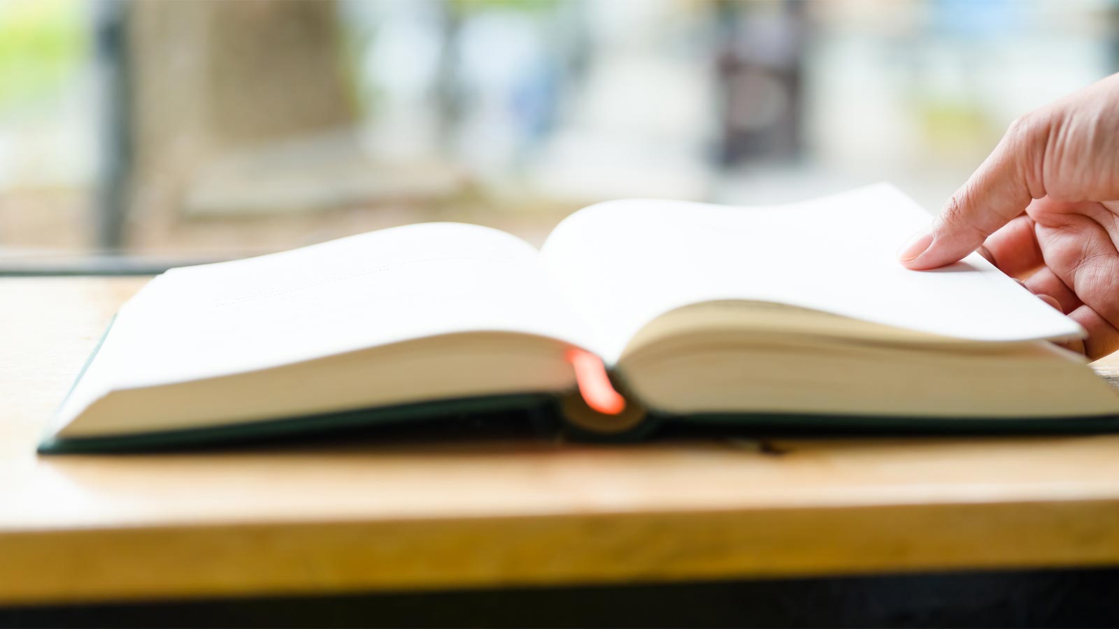 upclose image of a persons hand flipping pages in a book