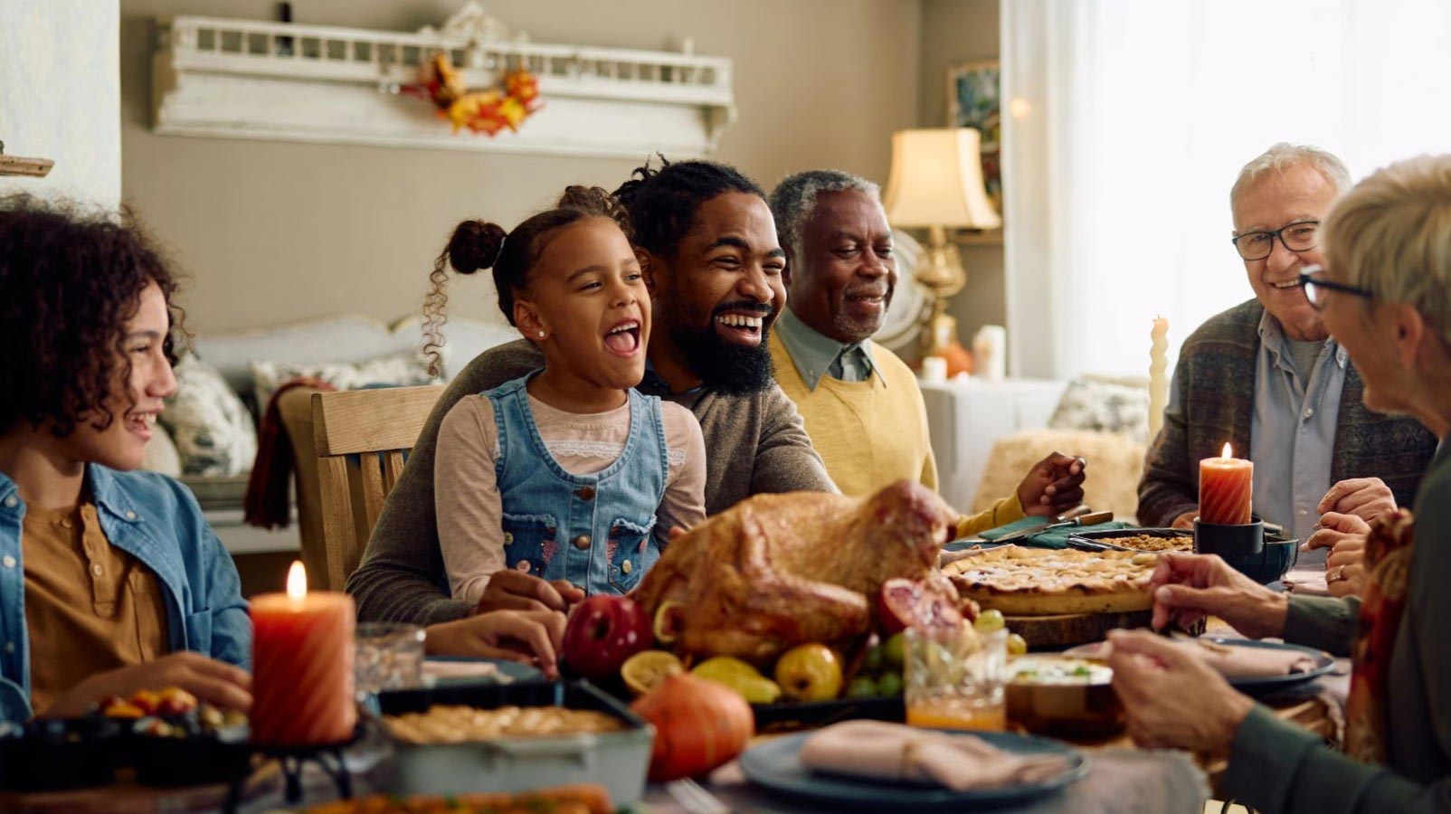Happy extended family having fun while gathering at dining table on Thanksgiving.