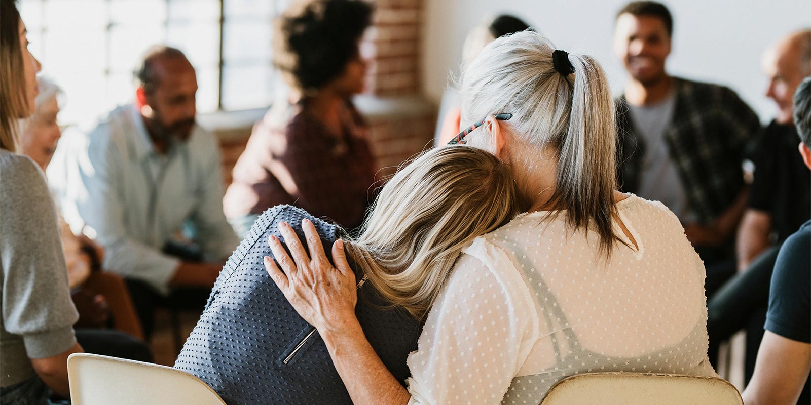 Older woman comforting girl in support group