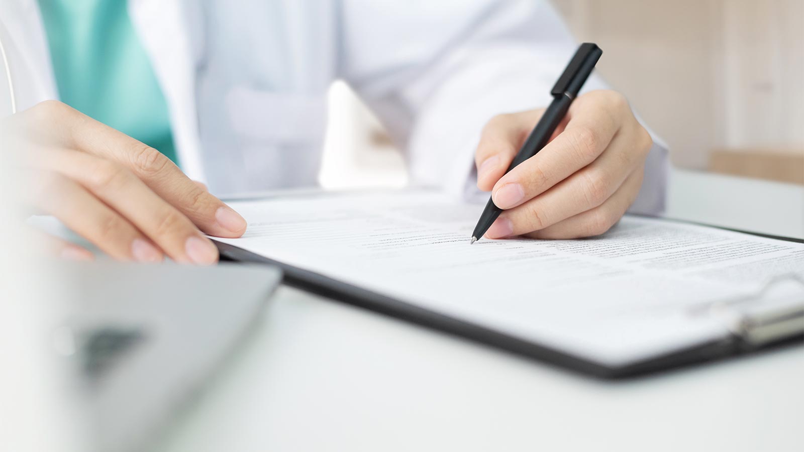 Female medical worker writing on document on clipboard in medical office