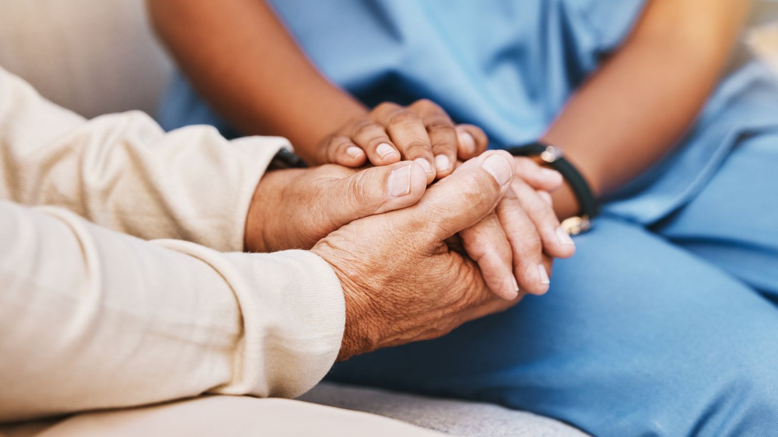 close up of patient and healthcare worker holding hands